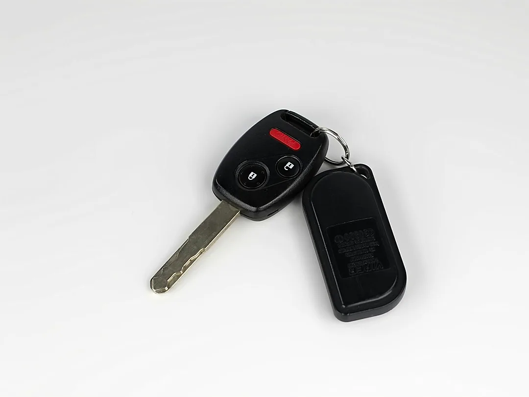 A car key with its remote fob, on white
